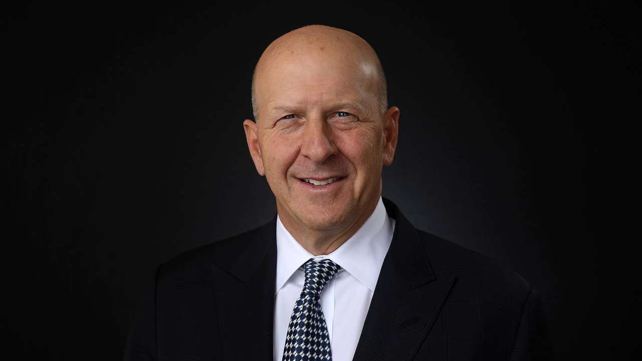 Man in suit against dark background.